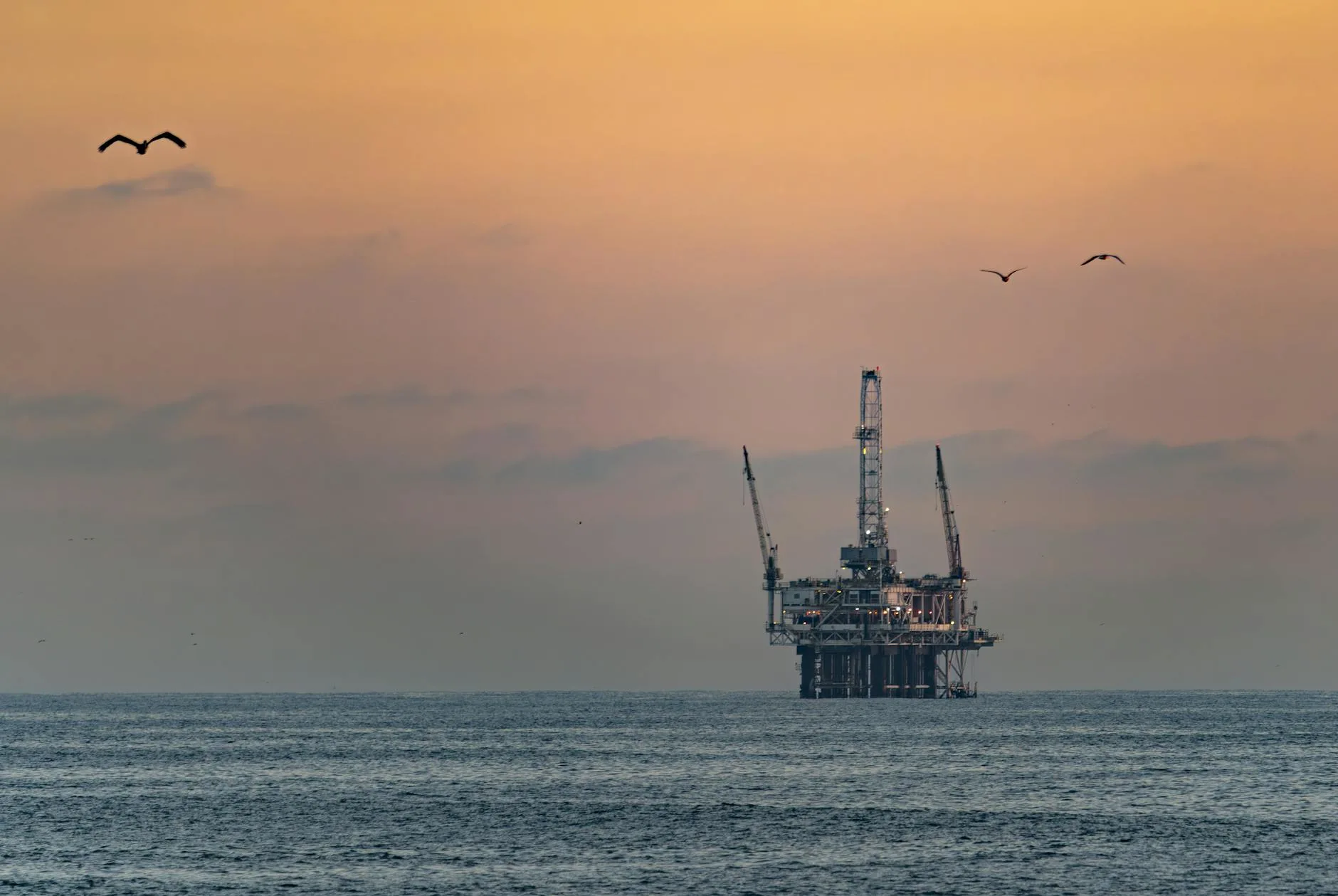 Oil platform silhouetted against a vibrant sunset in Huntington Beach, California.