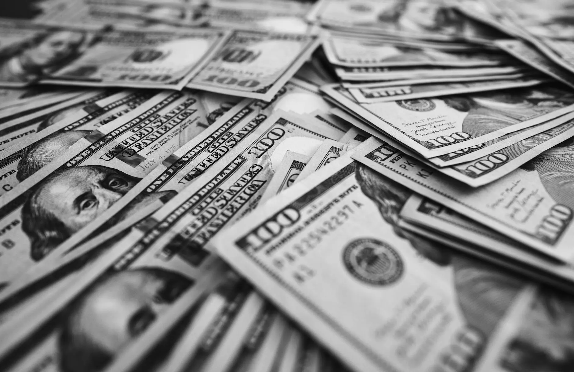 Monochrome image of scattered US hundred dollar bills representing wealth and prosperity.