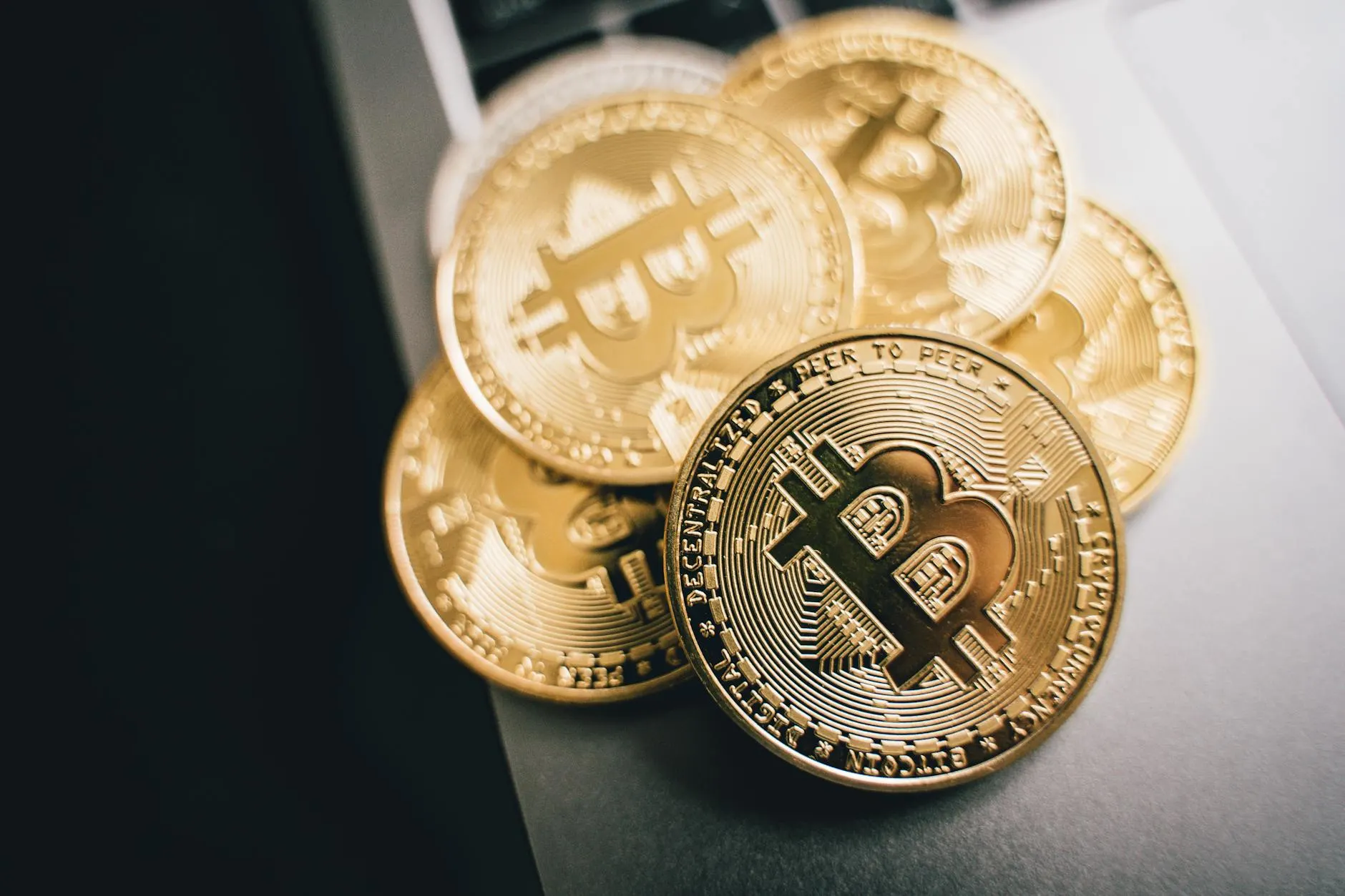 Close-up of golden Bitcoin coins on a laptop keyboard, symbolizing cryptocurrency investment.