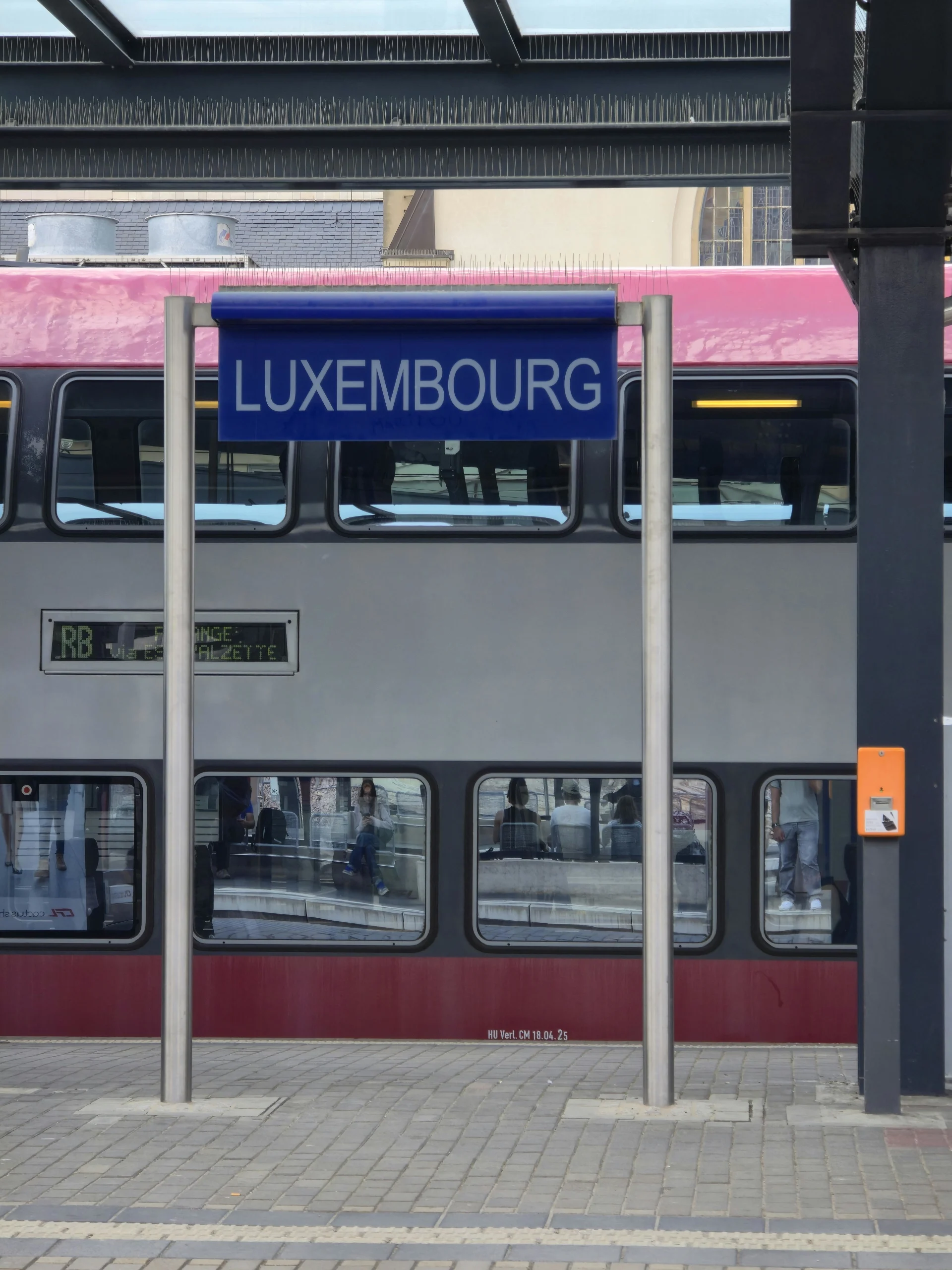 Luxembourg train station with double-decker train and station sign.