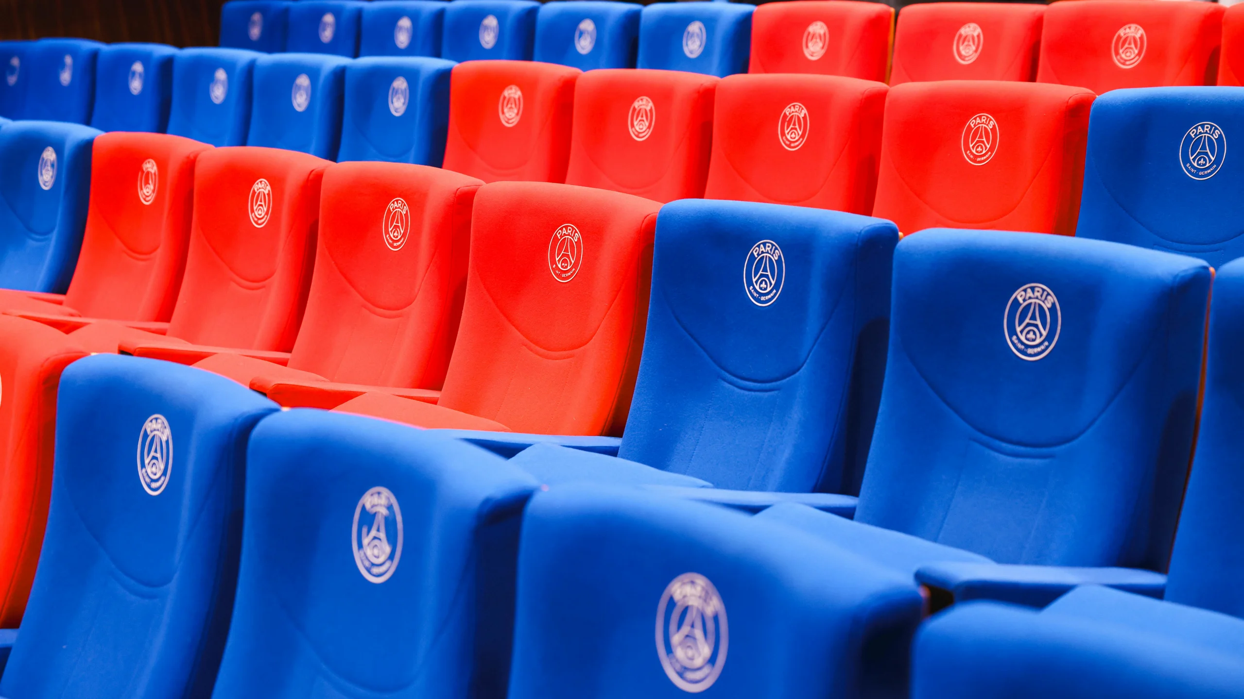 Rows of red and blue stadium seats featuring Paris emblems, vibrant and empty.