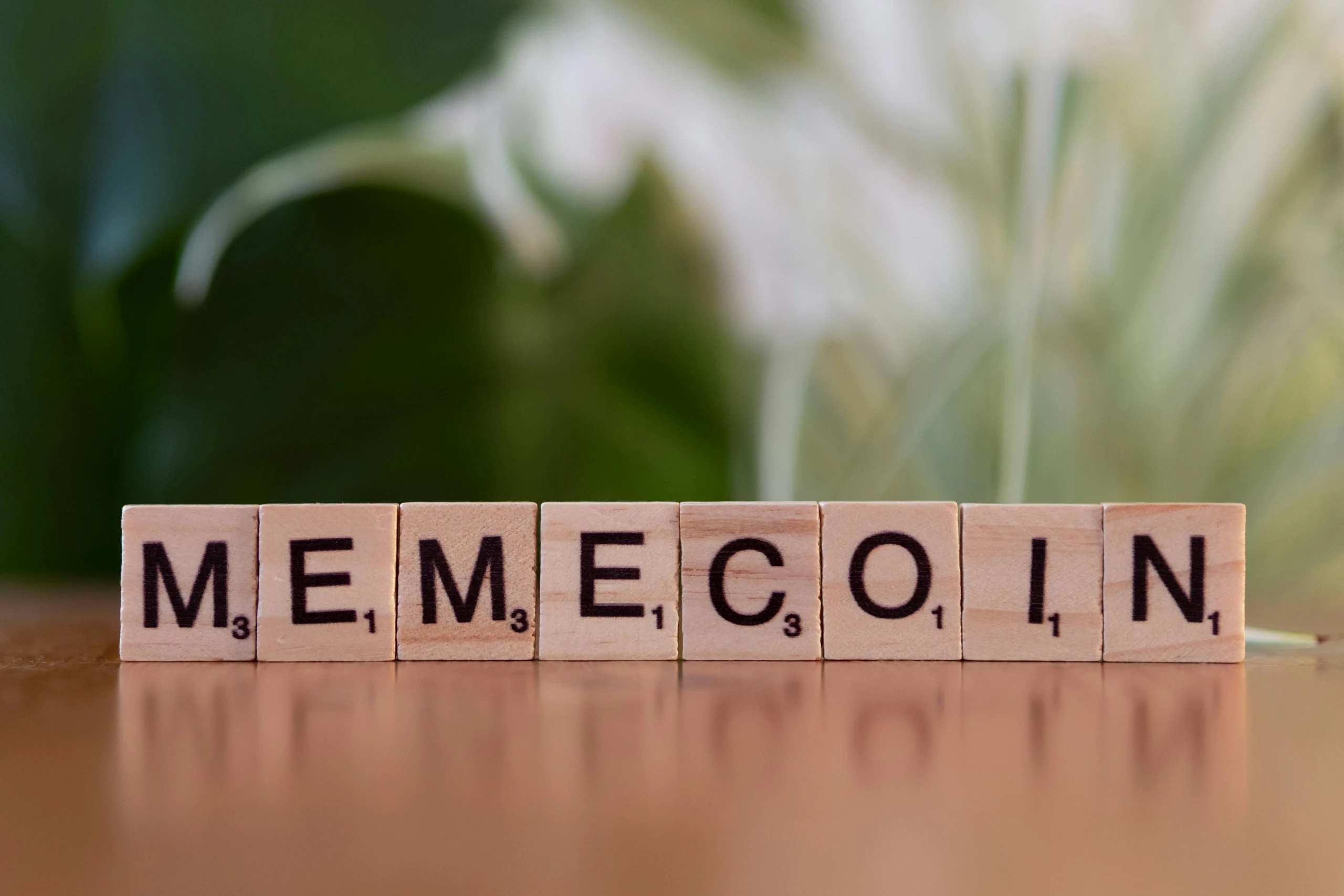 Wooden tiles spelling 'Memecoin' on a blurred background.