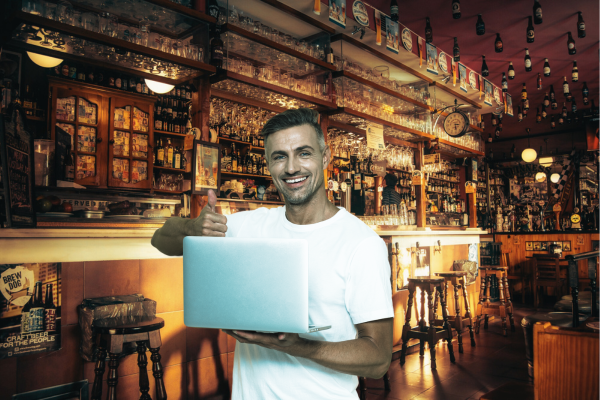 Person working on a laptop in a cozy pub environment representing the pub desking remote work trend