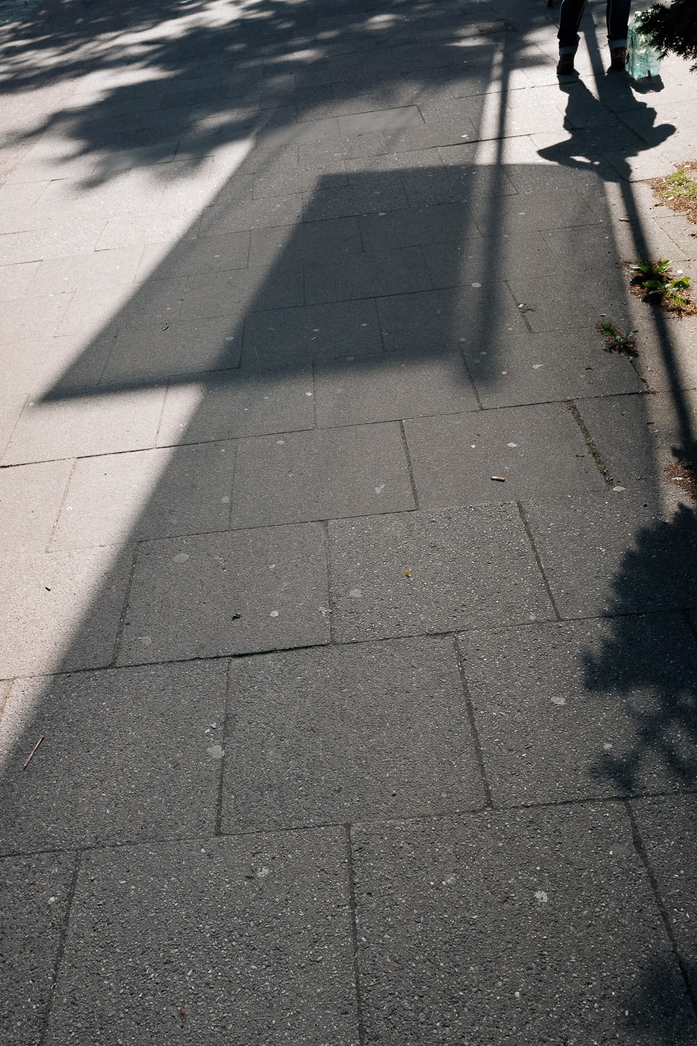 High contrast image with long shades made by two banners, and the shadow of a person talking on the phone while their water rests on the floor.