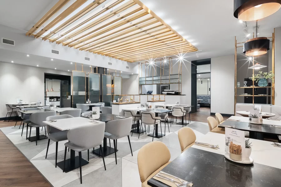 Helles Hotelrestaurant im Radisson Blu Prague mit klarer Linienführung, weißen Möbeln und goldenen Akzenten.