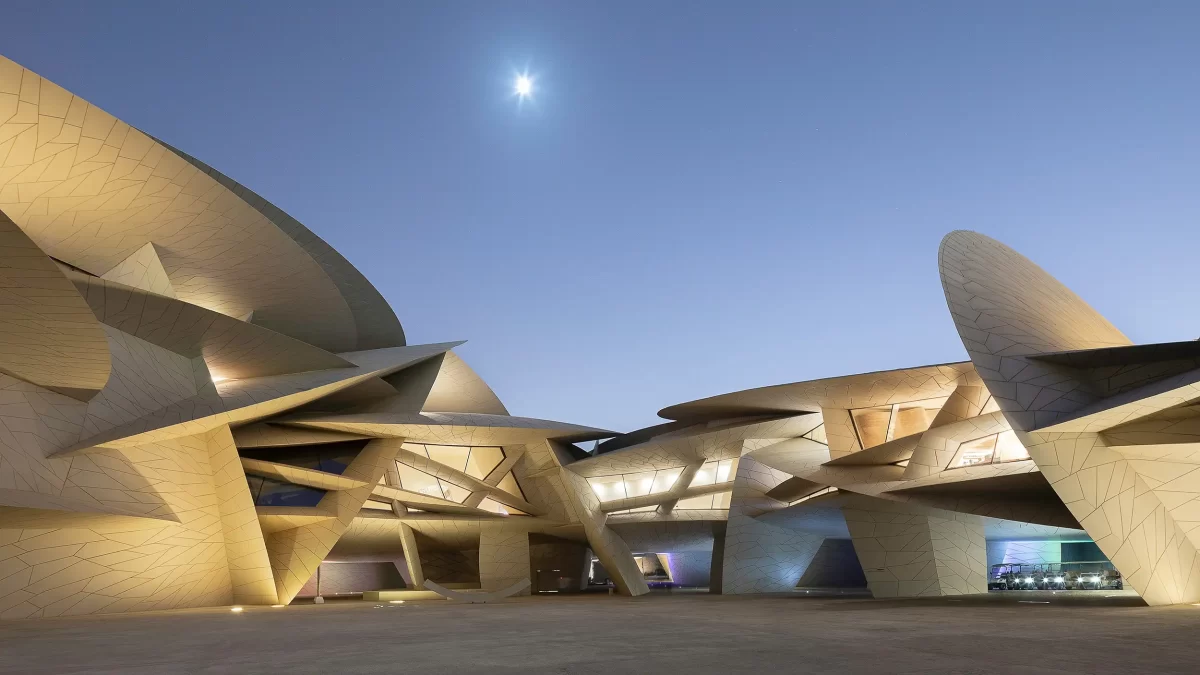 Eine minimalistische Weitwinkel-Architekturfotografie fängt den Blick auf den Innenhof des Nationalmuseums von Katar in Doha ein, ein Gebäude von Jean Nouvel, aufgenommen an der Schwelle zwischen der blauen Stunde und der Nacht.