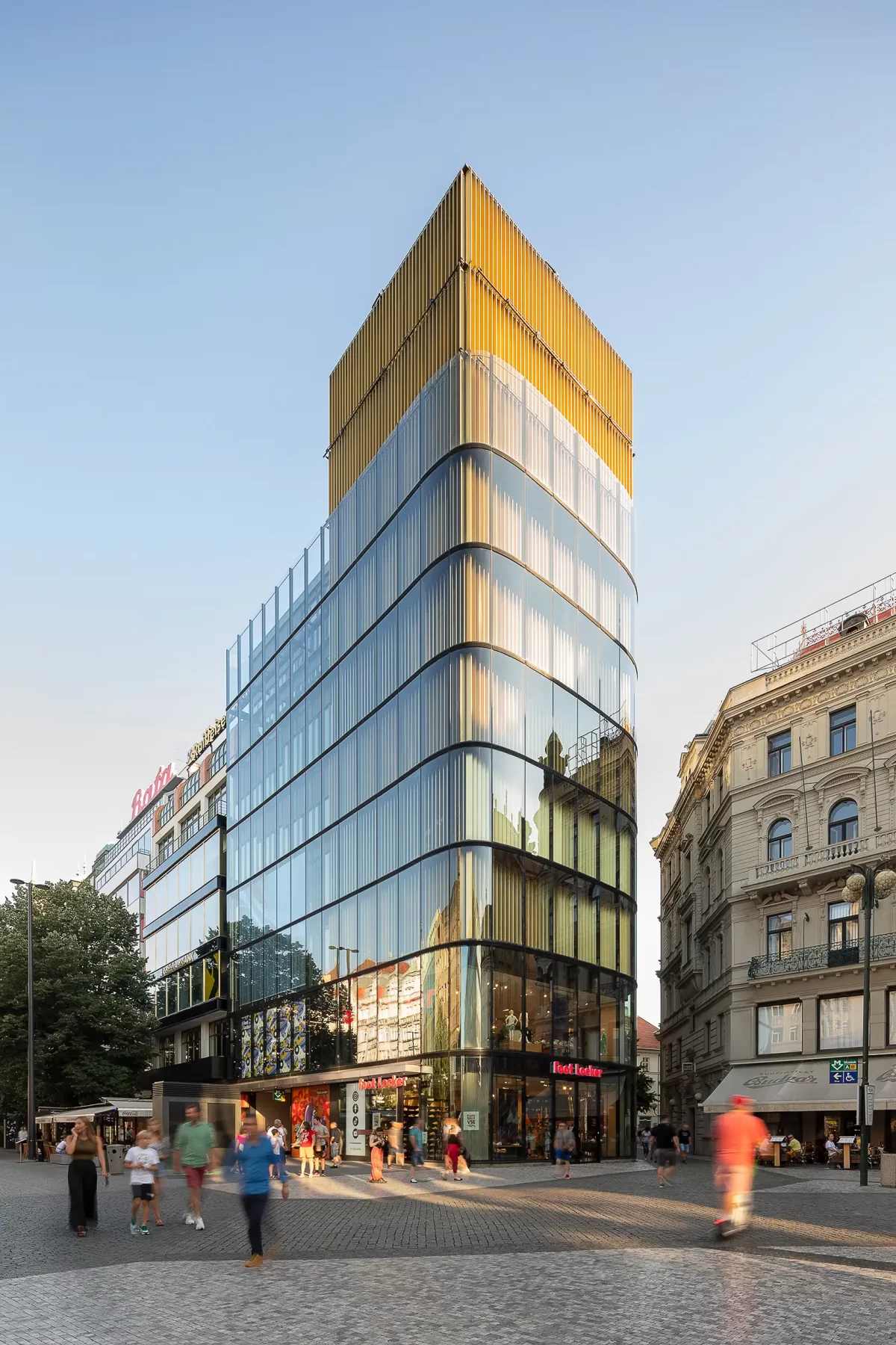 Vertikální fotografie moderní budovy Paláce Euro na pražském Václavském náměstí, pořízená během zlaté hodiny.