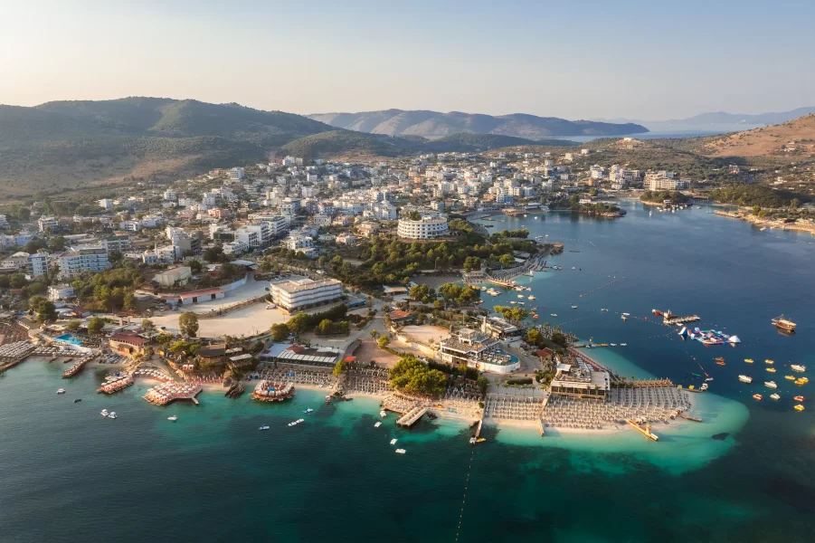 Luftaufnahme eines Resorts bei Ksamil 7 in Albanien bei Sonnenaufgang mit Blick auf Strand und umliegende Küstenlandschaft.