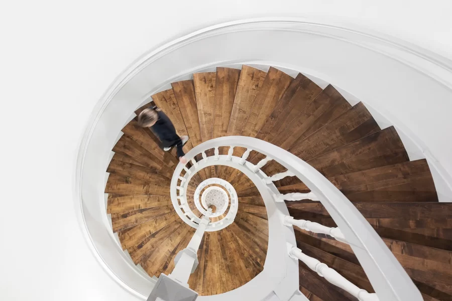 A view down on a motion blurred person descending a wooden spiral staircase in the Althörnitz Castle Hotel.