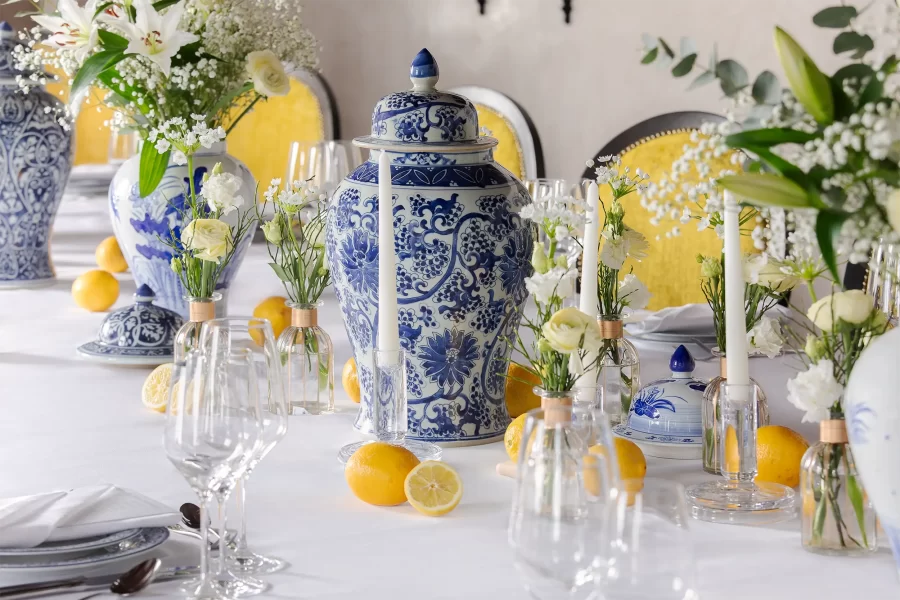 Hotelfotografie eines Hochzeitstisch-Details im italienischen Stil, dekoriert mit blau-weißem Porzellan, weißen Blumen und Zitronen.