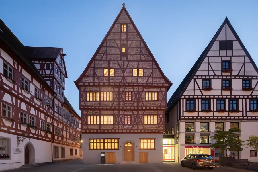 Frontalansicht der historischen, Fachwerkfassade des Hotel Krone in Oettingen am Marktplatz während der blauen Stunde.