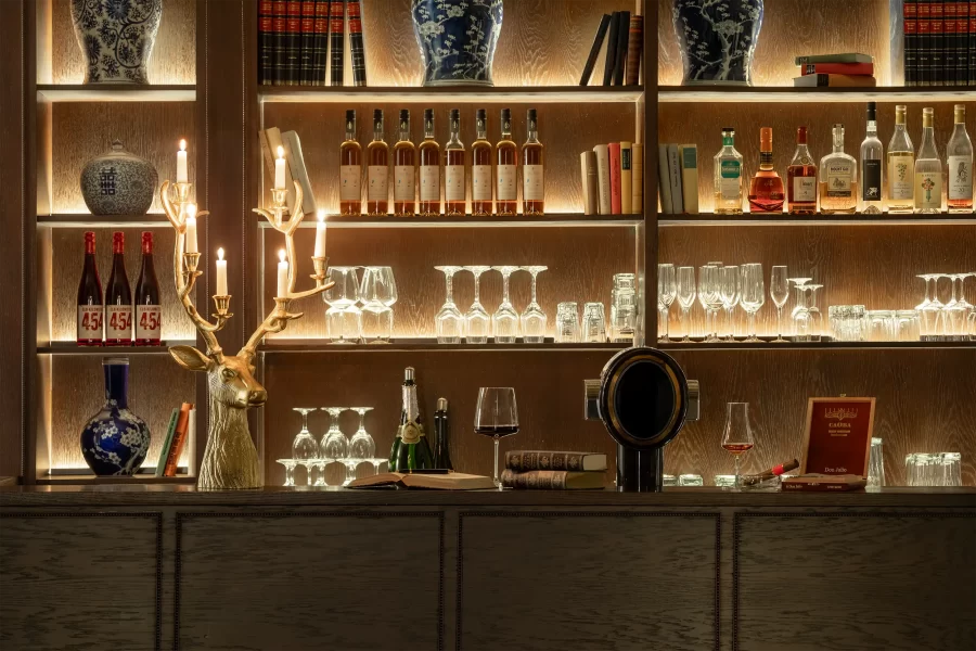 Detailaufnahme der beleuchteten Bar im Schlosshotel Althörnitz mit Weinflaschen, Gläsern und dekorativen Elementen in warmem Abendlicht.