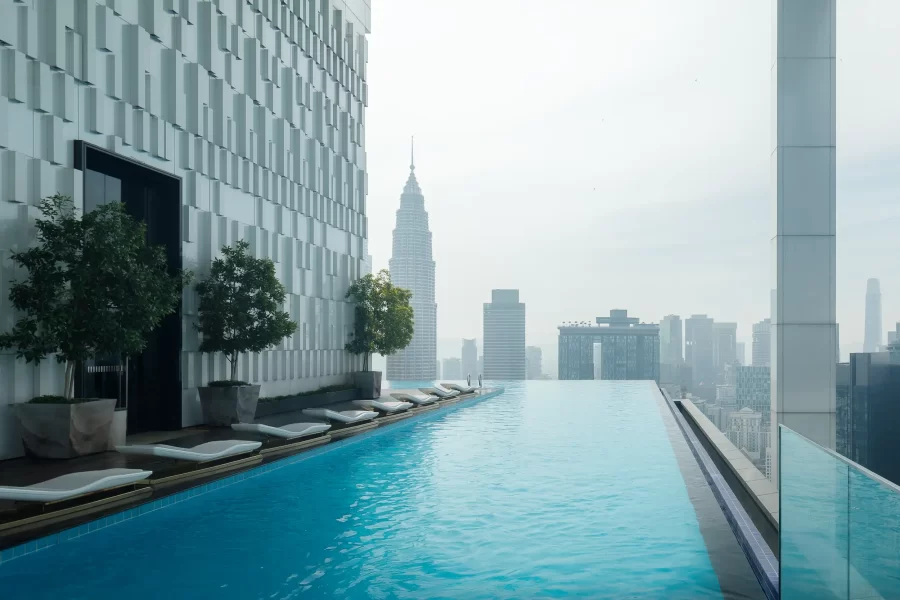 Rooftop-Infinitypool der ICC Ipoh Town Premium Suites by IWH mit ruhiger Wasseroberfläche und Skyline von Kuala Lumpur im Morgenlicht.