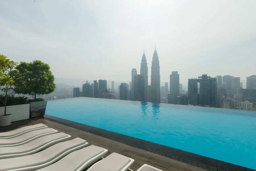 Infinitypool auf einer Dachterrasse in Kuala Lumpur mit Blick auf die Petronas Towers bei Sonnenaufgang.