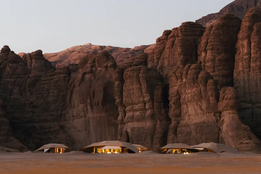 Dünenvillen des Banyan Tree AlUla Resorts vor den Sandsteinformationen der Wüste bei Sonnenuntergang.