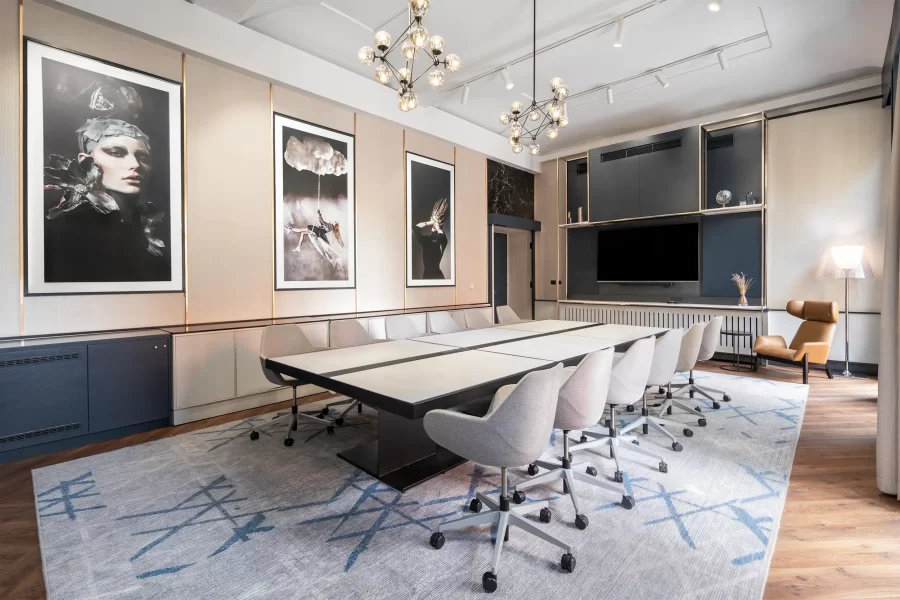 Hotel meeting room Stylish in Radisson Blu Prague equipped with a big table in the center with six chairs from each site, artworks on the wall, and a comfortable armchair with a lamp in the corner.