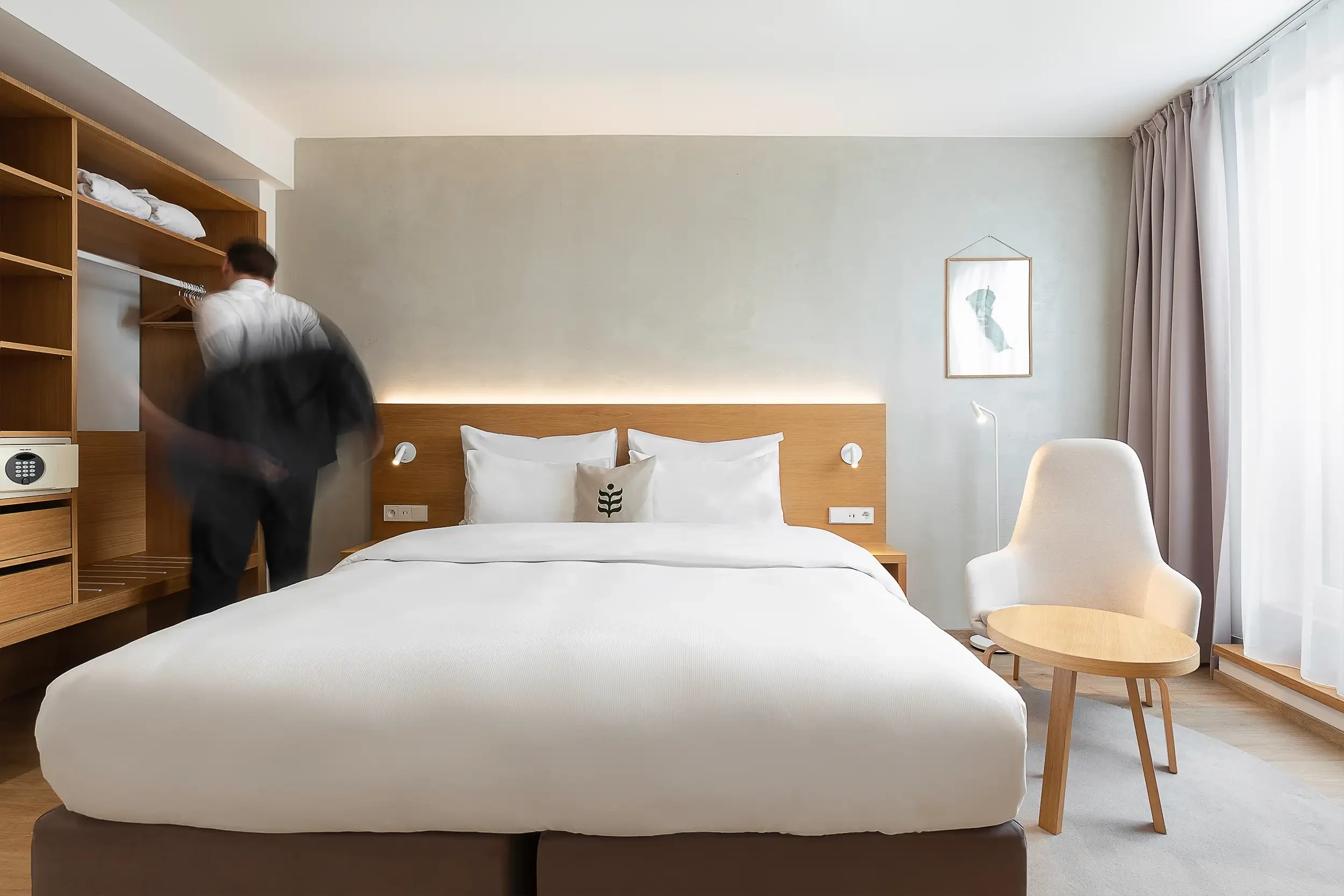 Botanique Premium King mit Balkon im Botanique Prag mit Kingsize-Bett und offenem Stauraum, Geschäftsmann in Bewegung unscharf im Hintergrund.