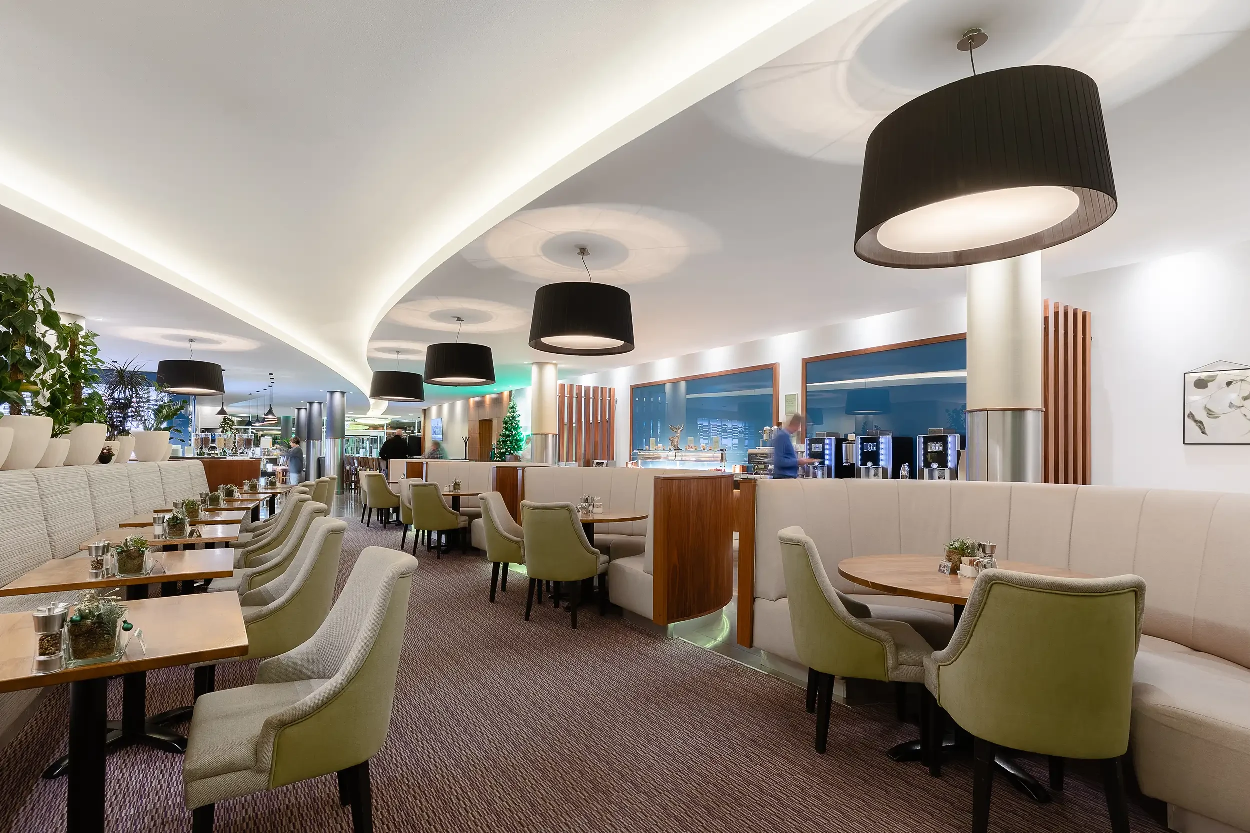 Restaurant mit organisch geformter Decke, runden Holzelementen und modernem Sitzbereich.