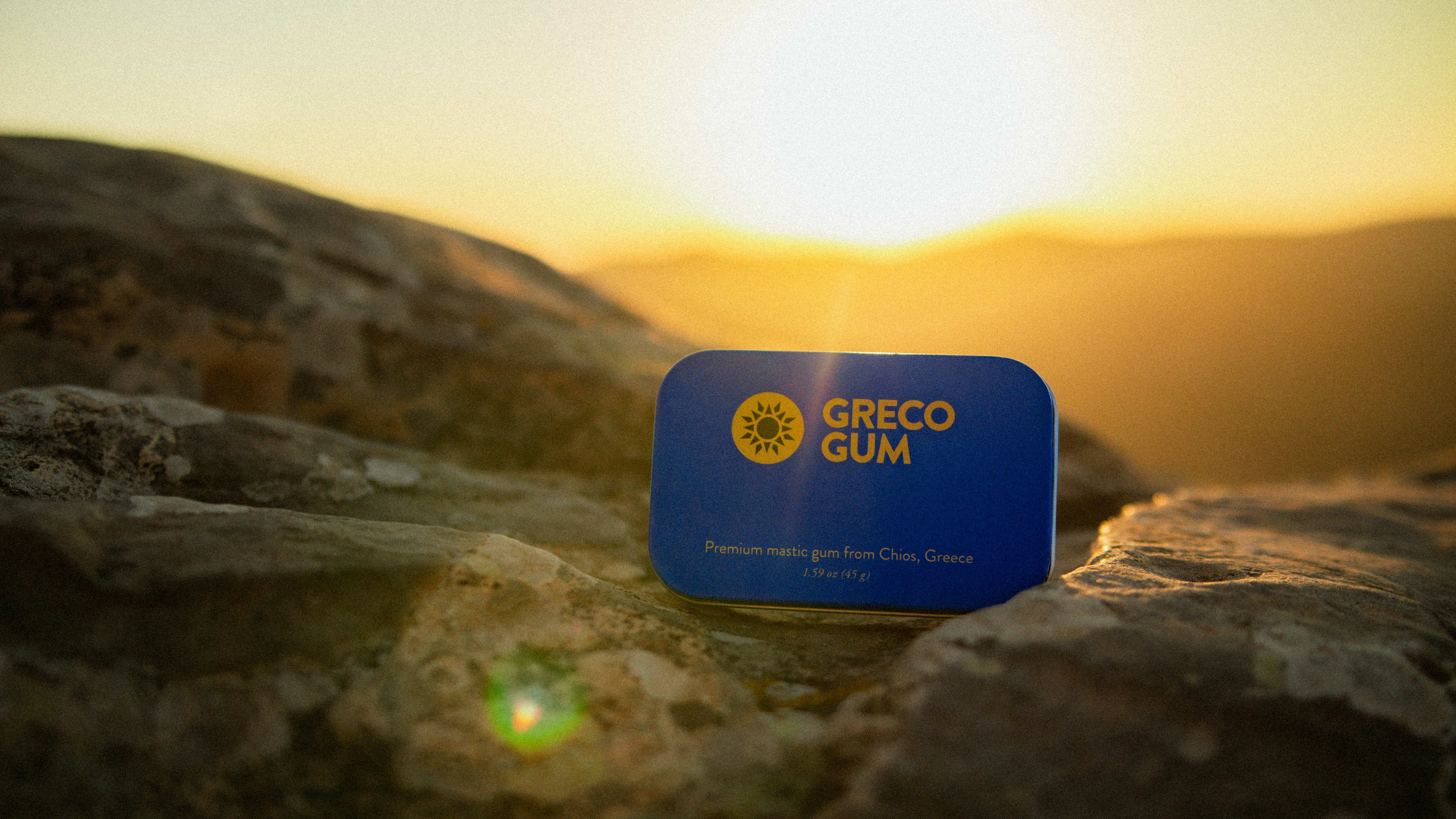 Greco Gum tin on rocks during sunset.