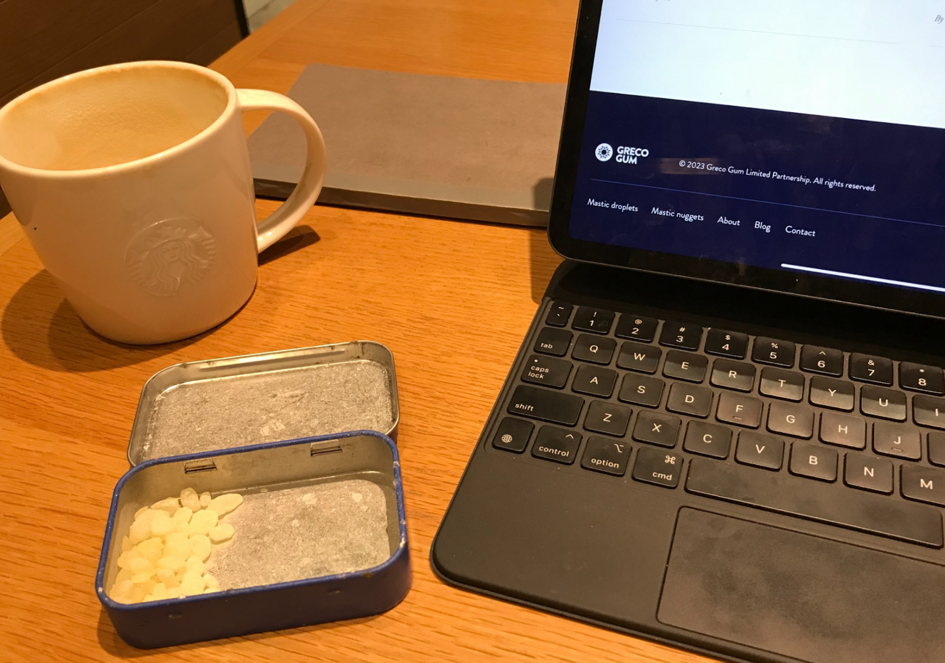 Desk with laptop and almost-empty tin of Greco Gum