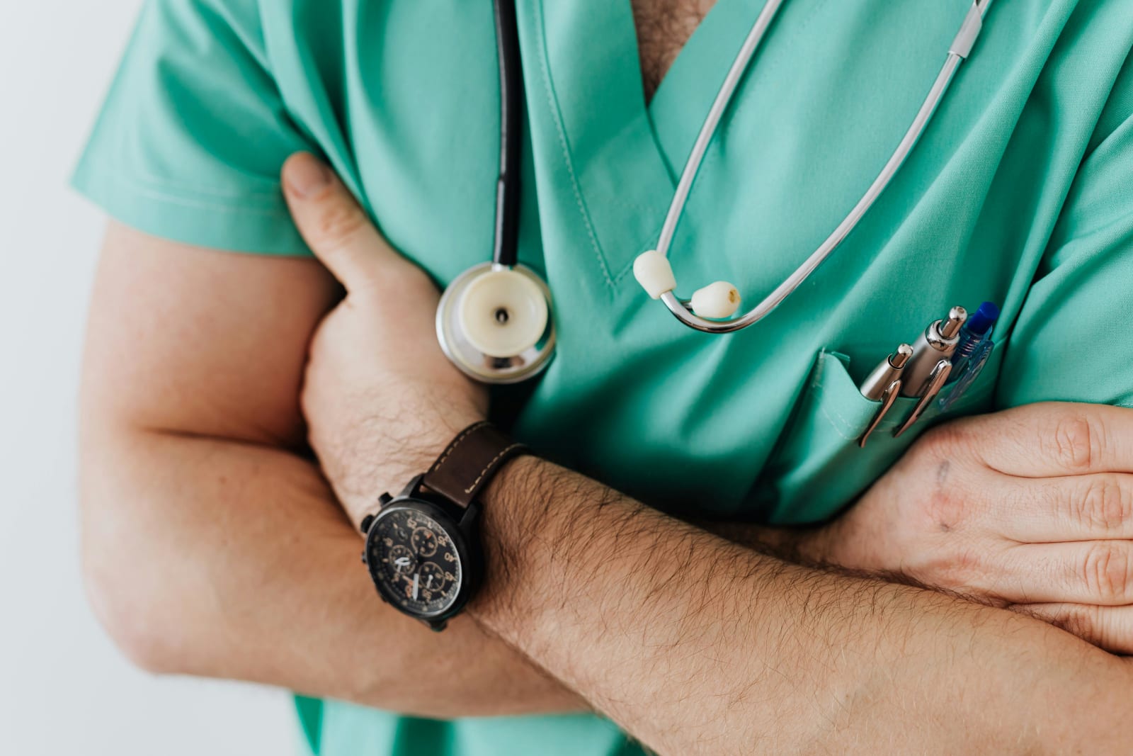 A doctor with a stethoscope around his neck crosses his arms