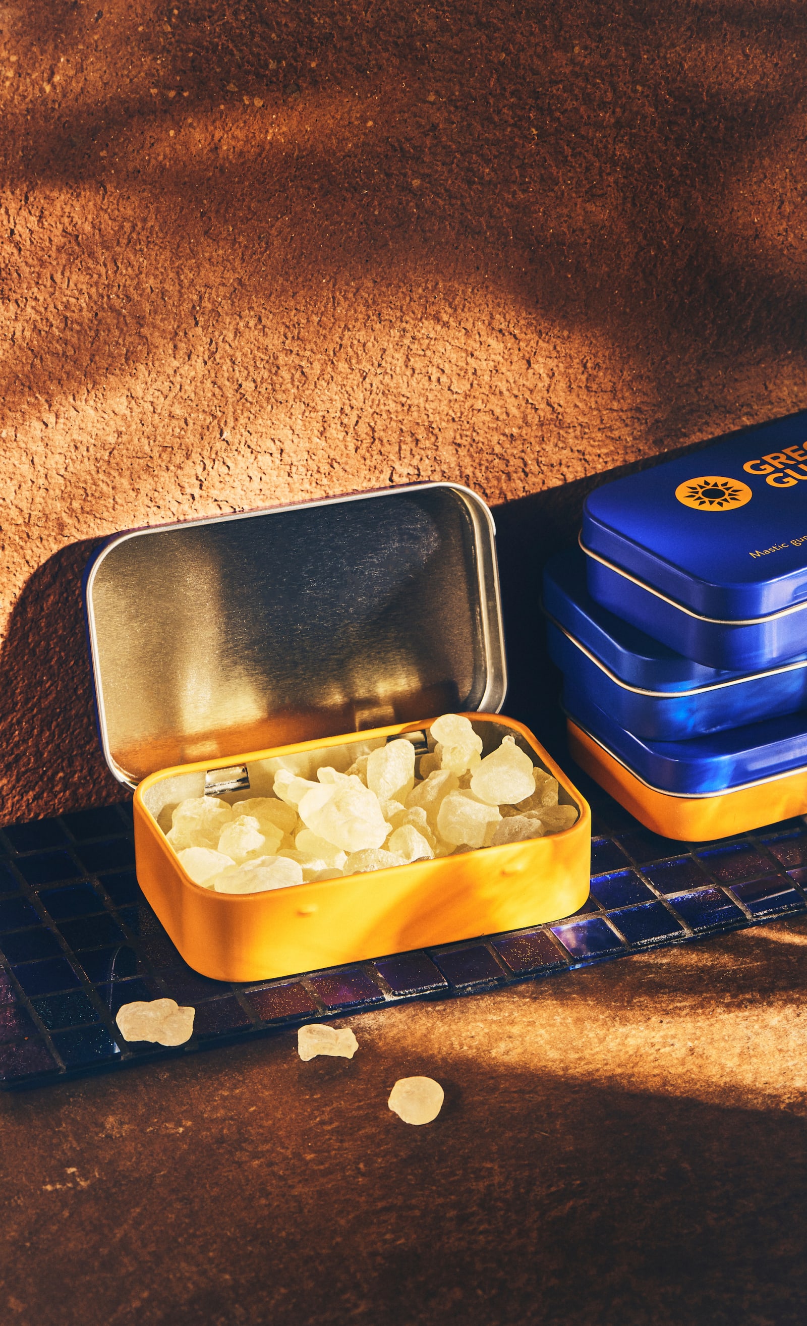 Open tin of mastic nuggets next to tins of droplets and nuggets.