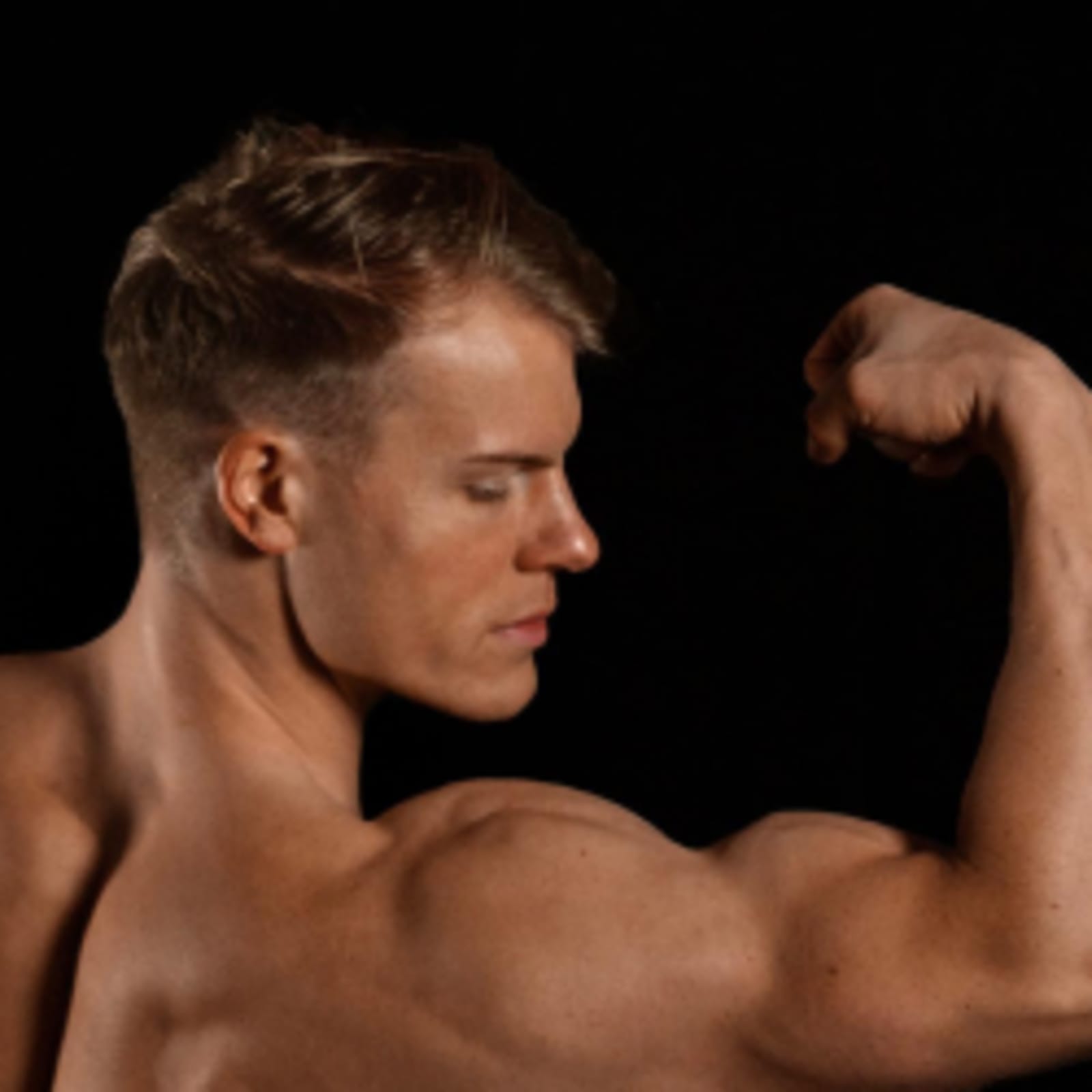 A side shot of a muscular man flexing his arm.
