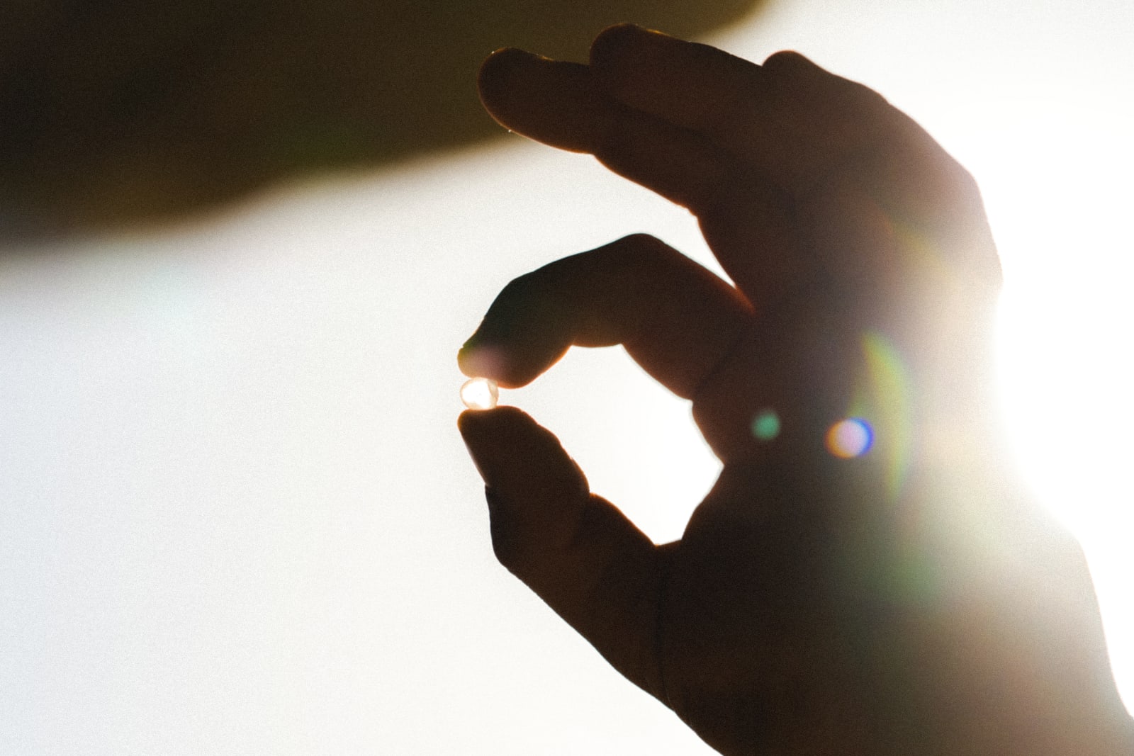 Hand holding mastic droplet in natural lighting.