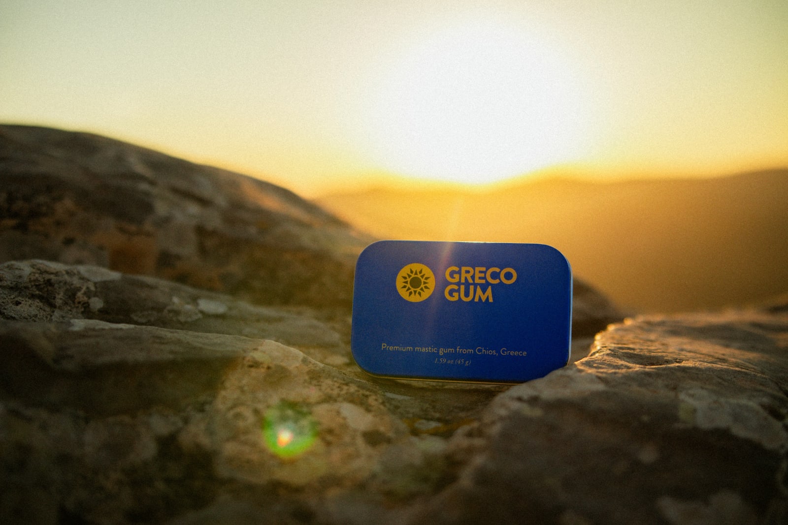 Greco Gum tin on rocks during sunset.
