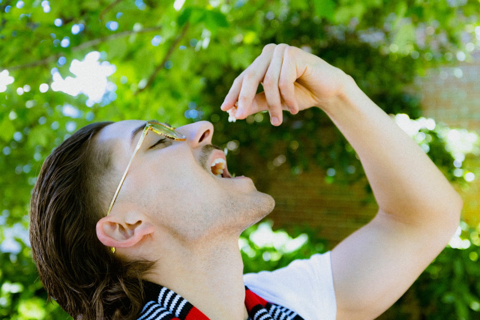 A man pours droplets of mastic gum into his mouth.