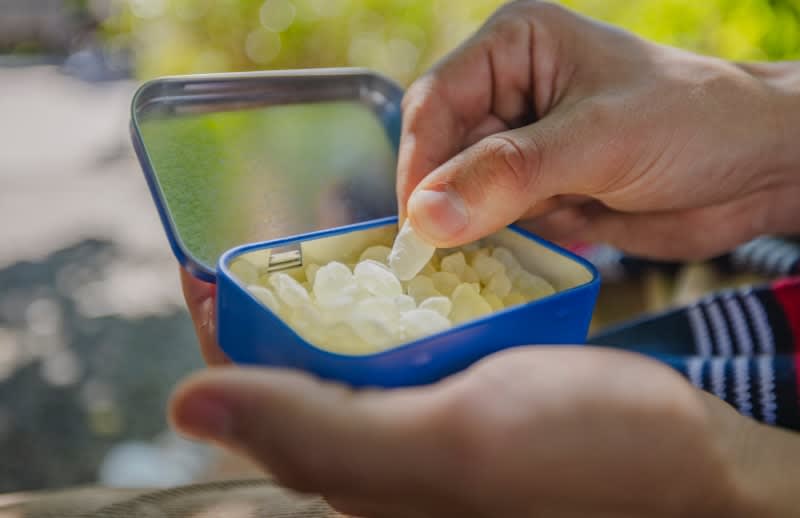 A man picks up a mastic gum nugget from a tin of Greco Gum