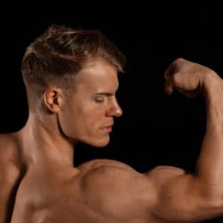 A side shot of a muscular man flexing his arm.