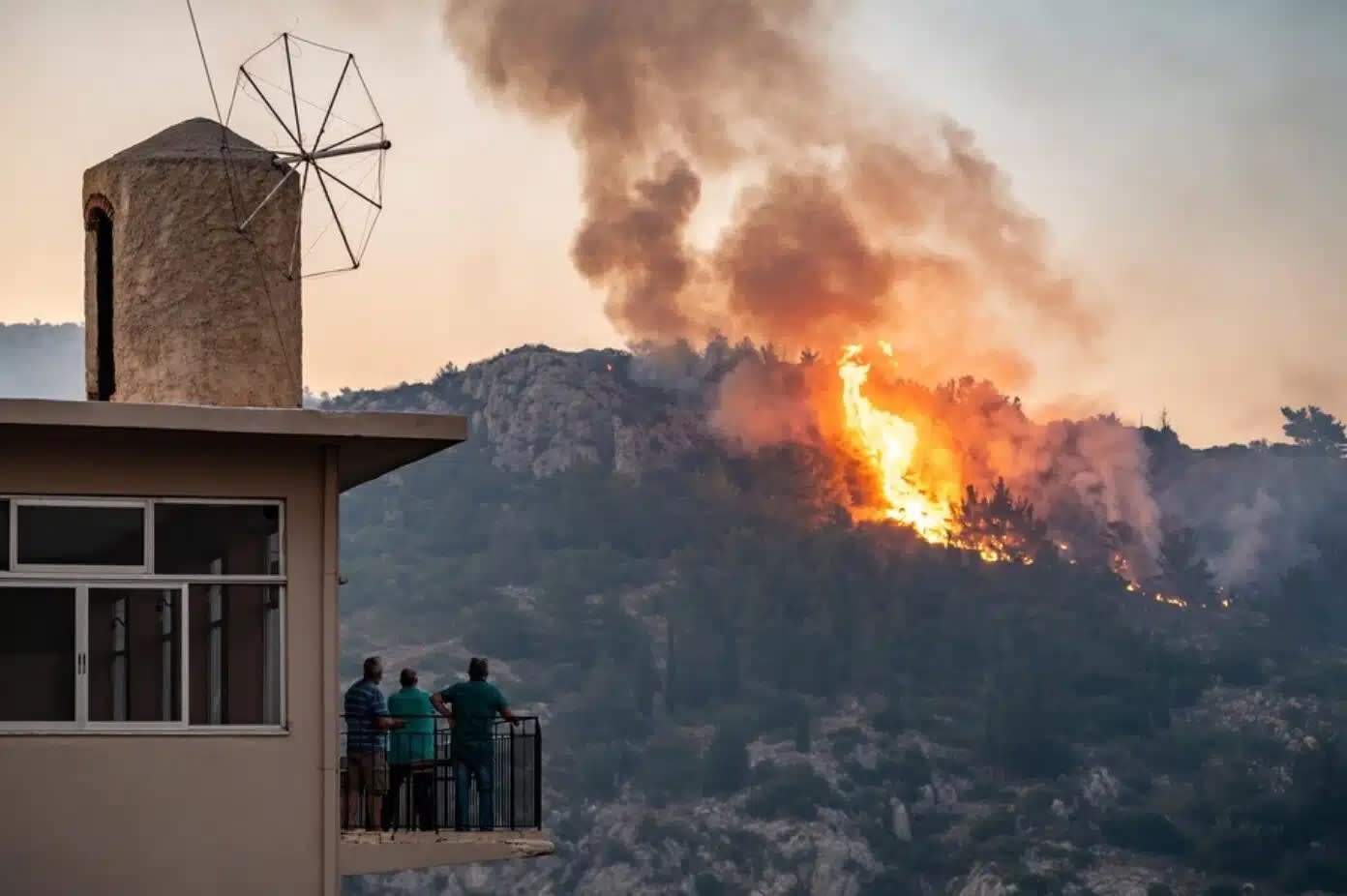 A family watches the Chios fire of 2012, which burned half of the island, from their balcony