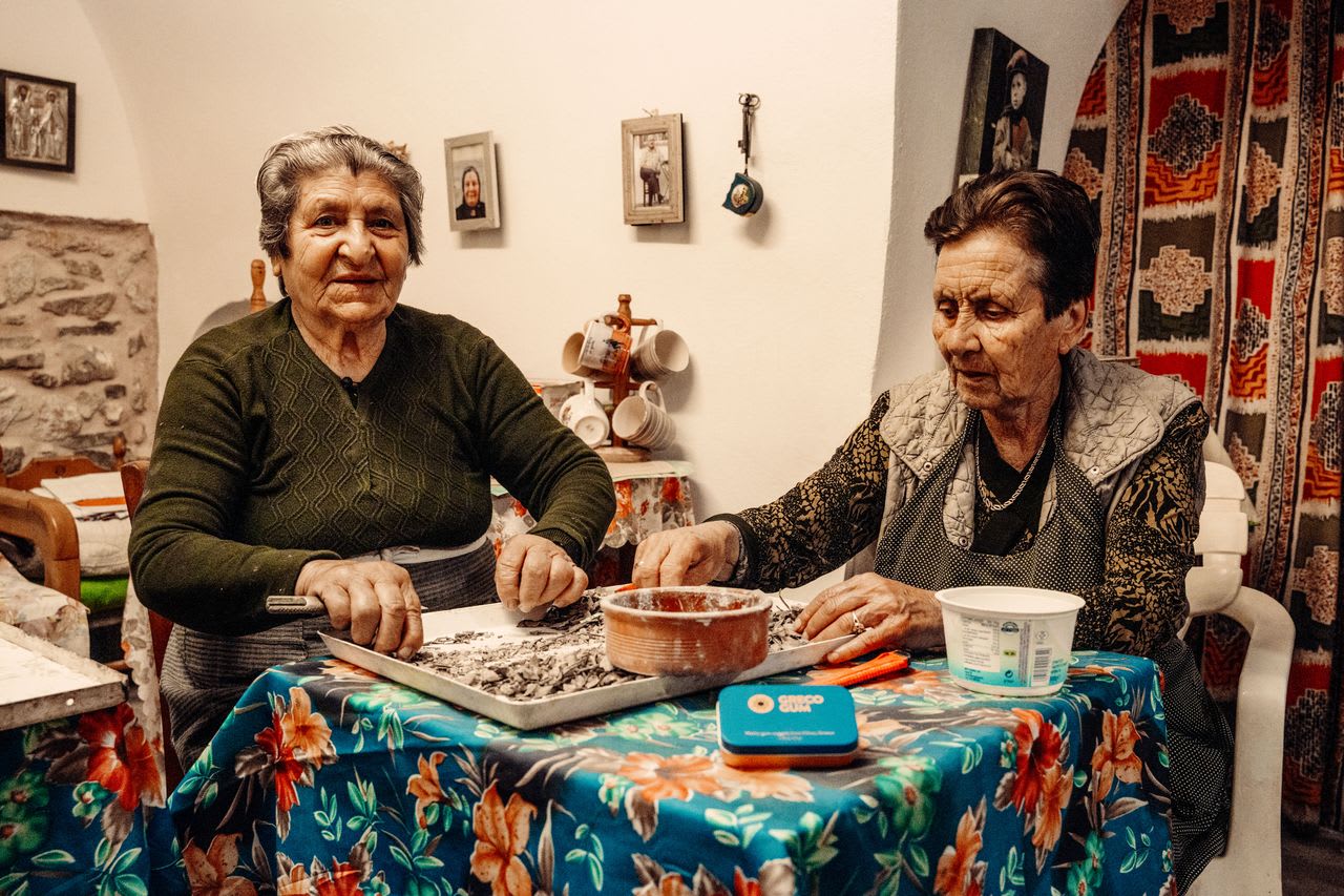 Two elderly women sit and clean mastic gum by hand