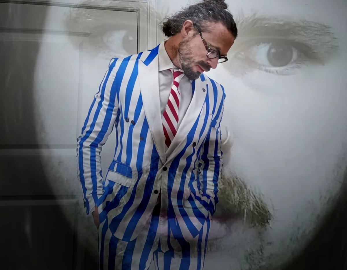 A man in a blue-and-white striped suit, in the colors of the Greek flag