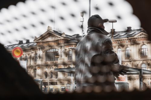 A man on the street seen through a grid