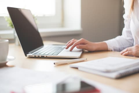 Fotographie einer Frau, die an ihrem Laptop arbeitet.