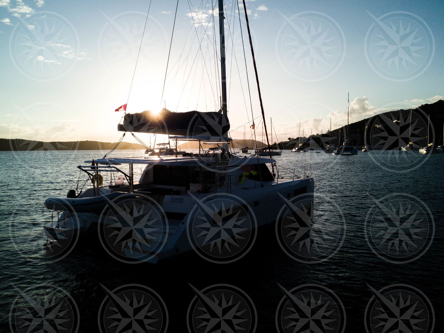 Yacht at anchor backlit by sunset