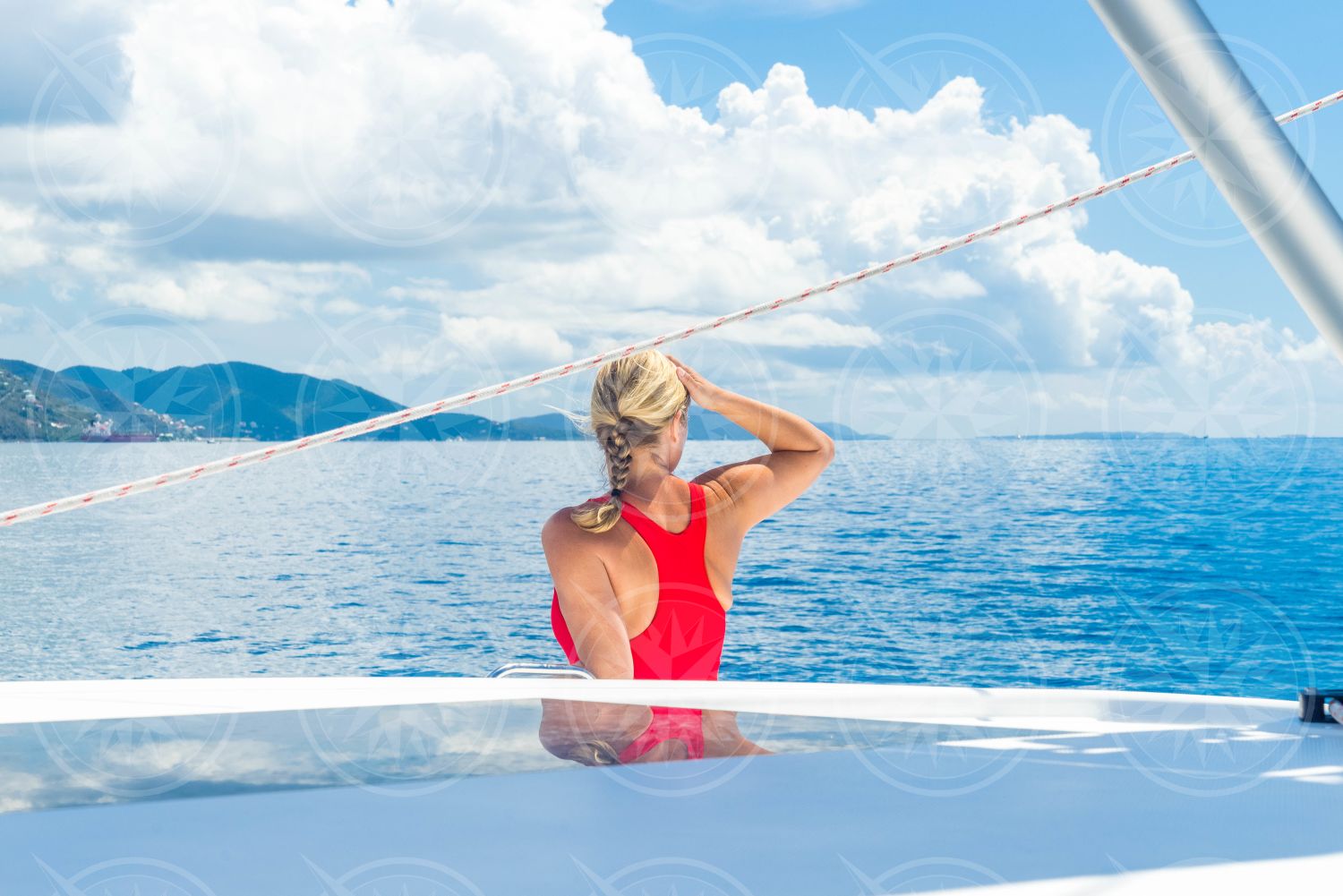 Woman in swimsuit on a sailboat looking to the horizon