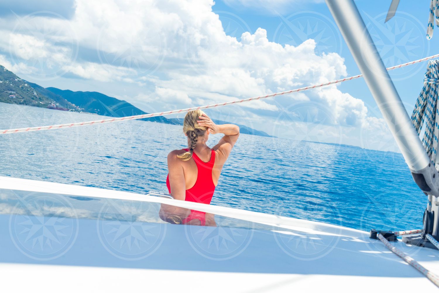 Woman in swimsuit on a sailboat looking to the horizon