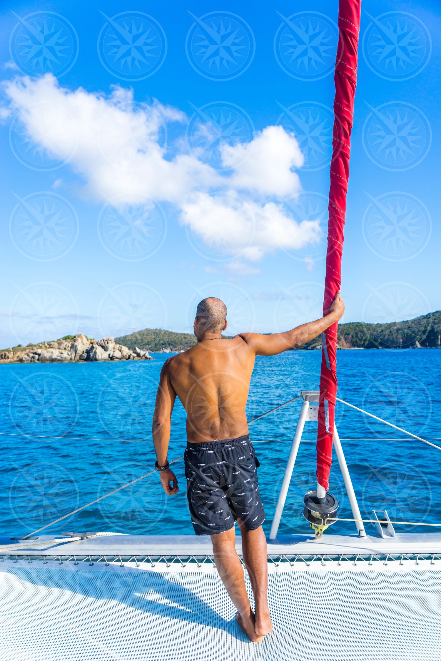 Man holding jib at bow of catamaran