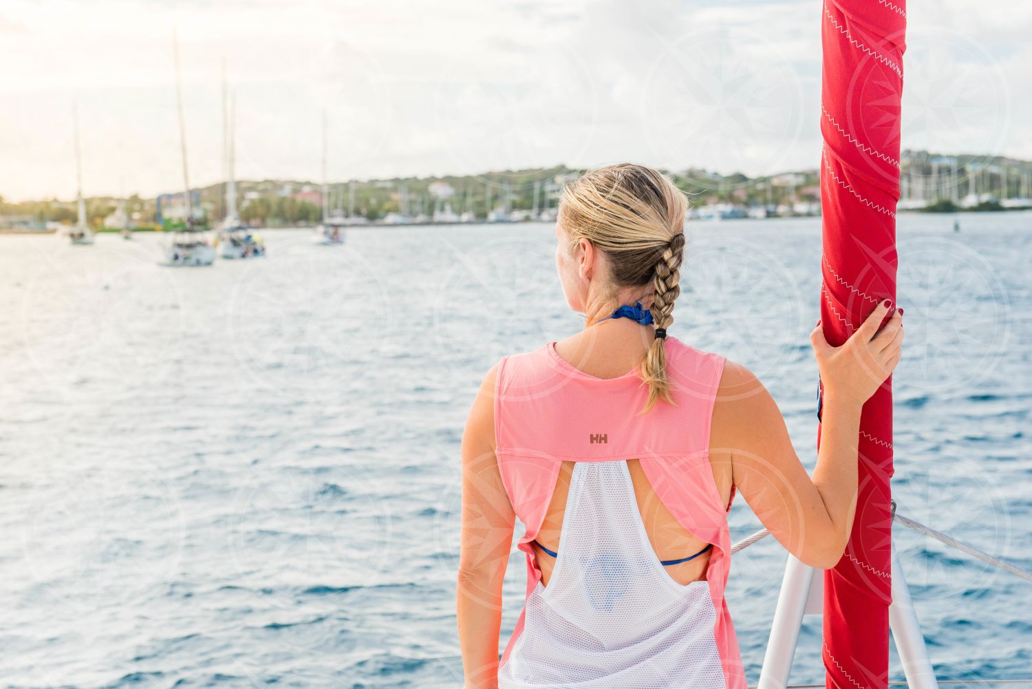 Woman holding furled jib at bow of yacht