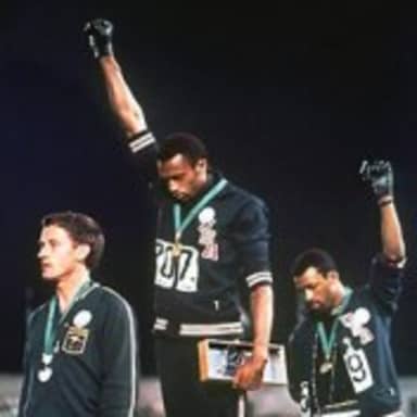 Awkward Olympics meme template: Three men on an Olympic podium, two with raised fists, one looking down.