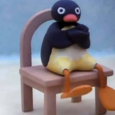 Angry Pingu meme template: A claymation penguin named Pingu sits on a small chair with his arms crossed and a stern, annoyed expression.