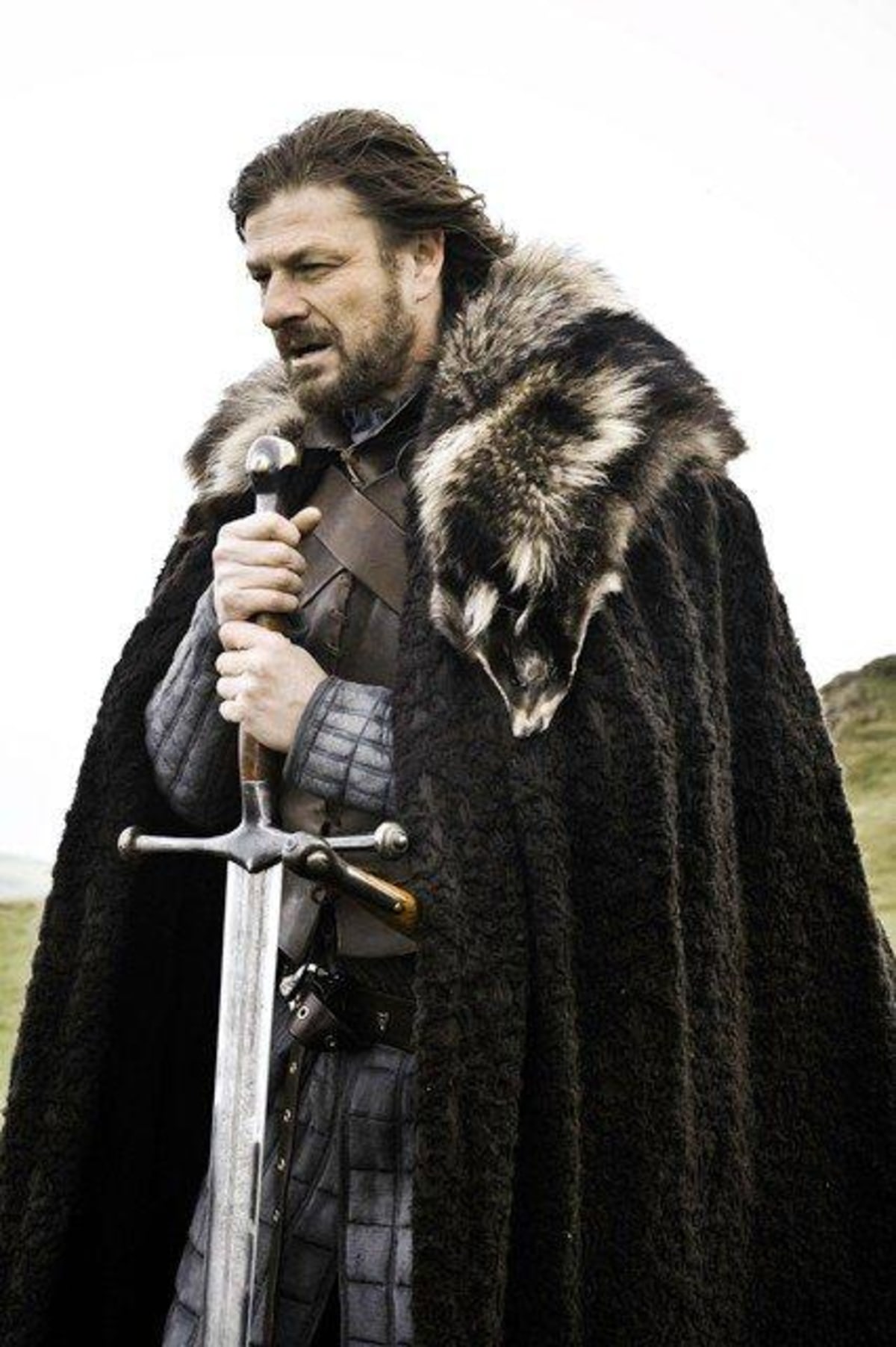 Brace Yourself meme template: A man in medieval attire, holding a sword and wearing a fur-lined cloak, looks determined and ready for action.
