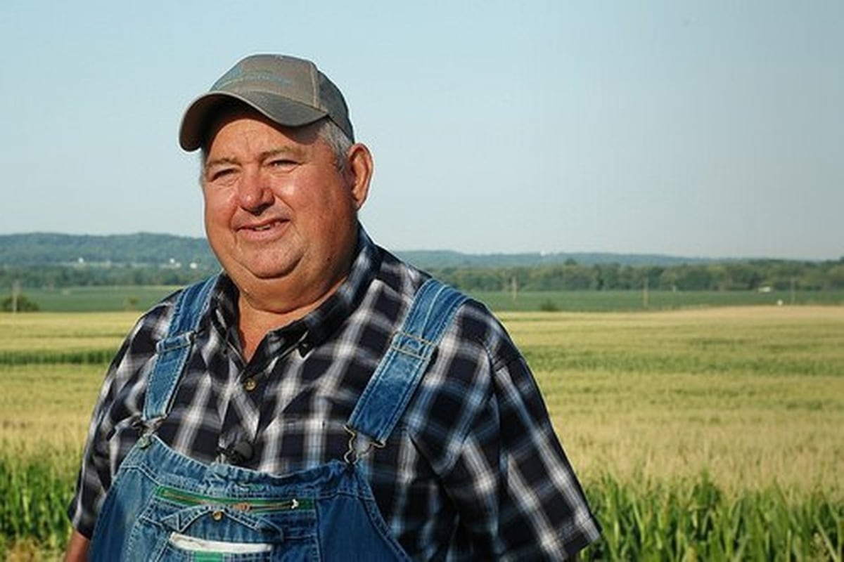 But It's Honest Work meme template: A man in overalls and a plaid shirt standing in a field, smiling.