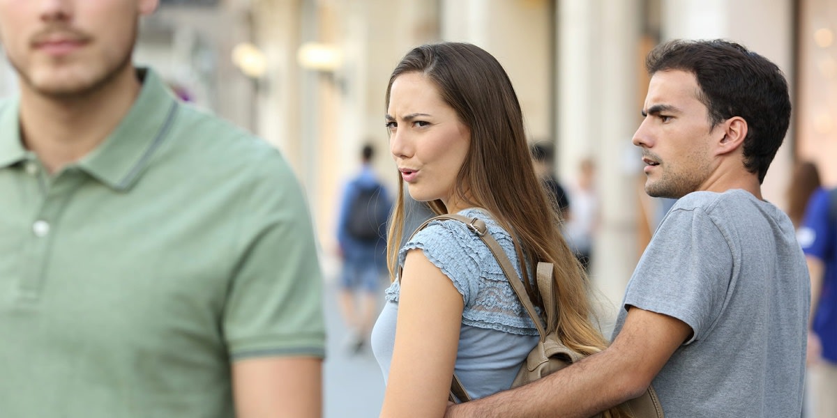 Distracted Girlfriend meme template: A man is walking with his girlfriend, but he looks back to check out another woman walking by.
