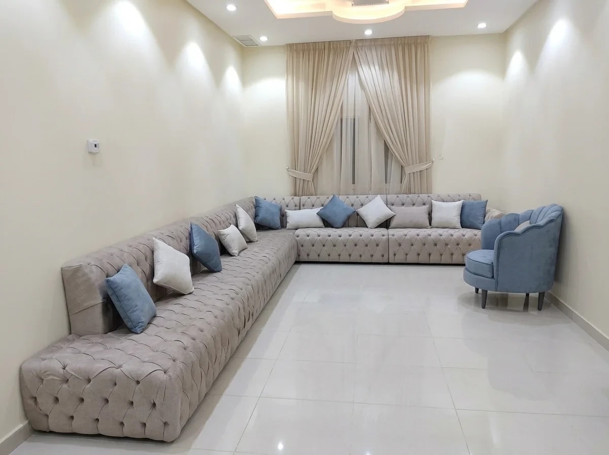 Main commercial studio photograph of low-profile diamond-tufted modular modern majlis in sand-taupe with accent pillows