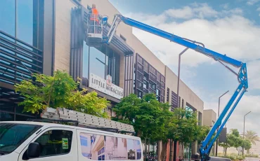 Liverpool Services staff are cleaning the side of a building using an extended crane. Liverpool Services staff are cleaning the side of a building using an extended crane.