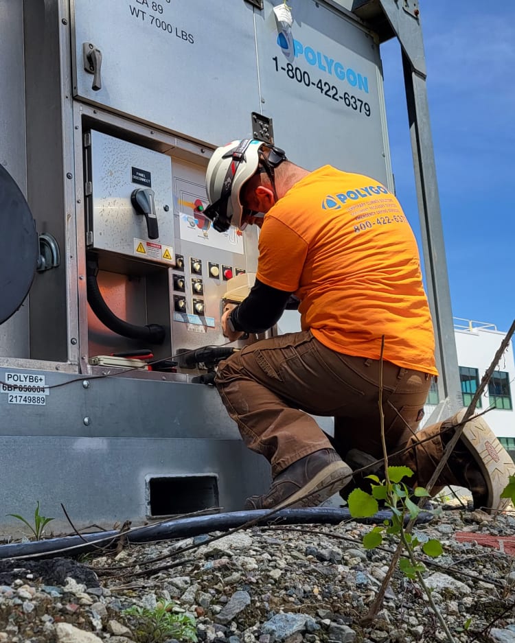 Worker performing maintenance on an electric climate control system at a construction or industrial site.